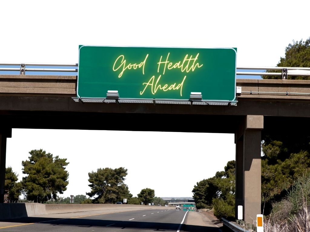 Road Sign stating "Good Health Ahead" with a straight road to your destination.